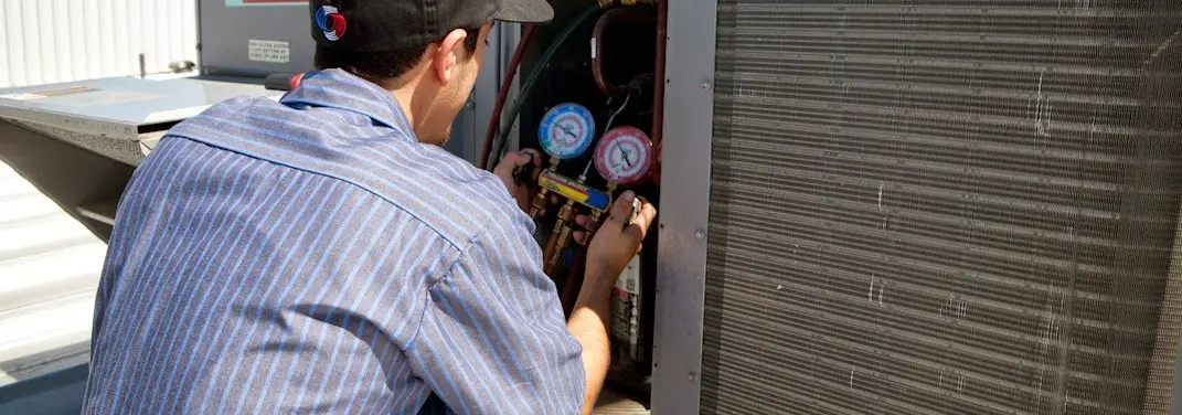 HVAC technician servicing a condenser unit in Warren