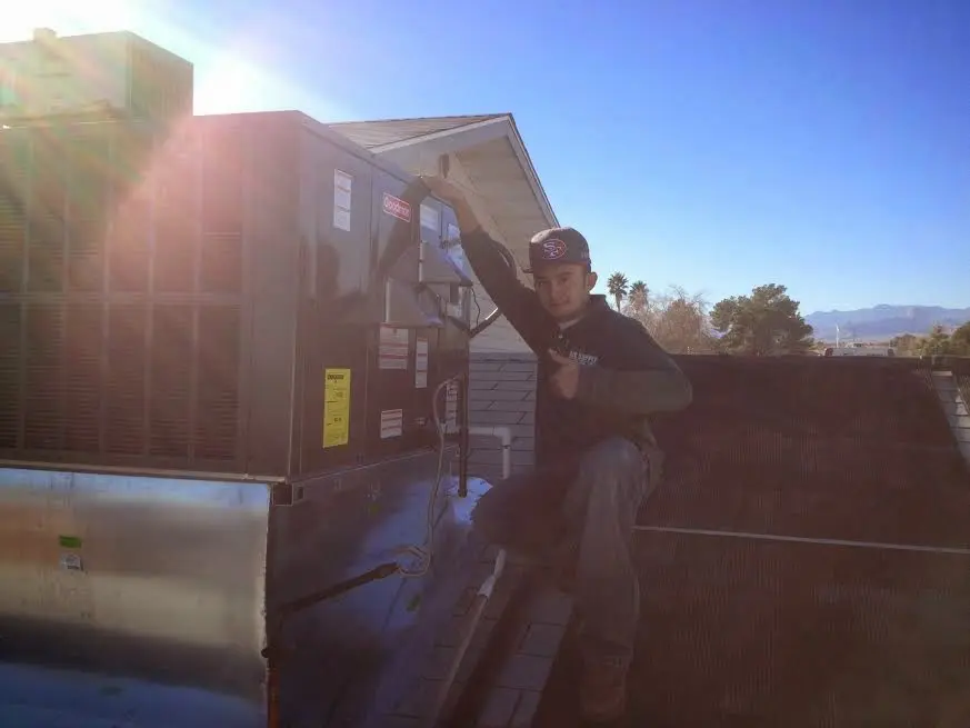 HVAC technician performing Air Duct Repair on a rooftop unit in Warren
